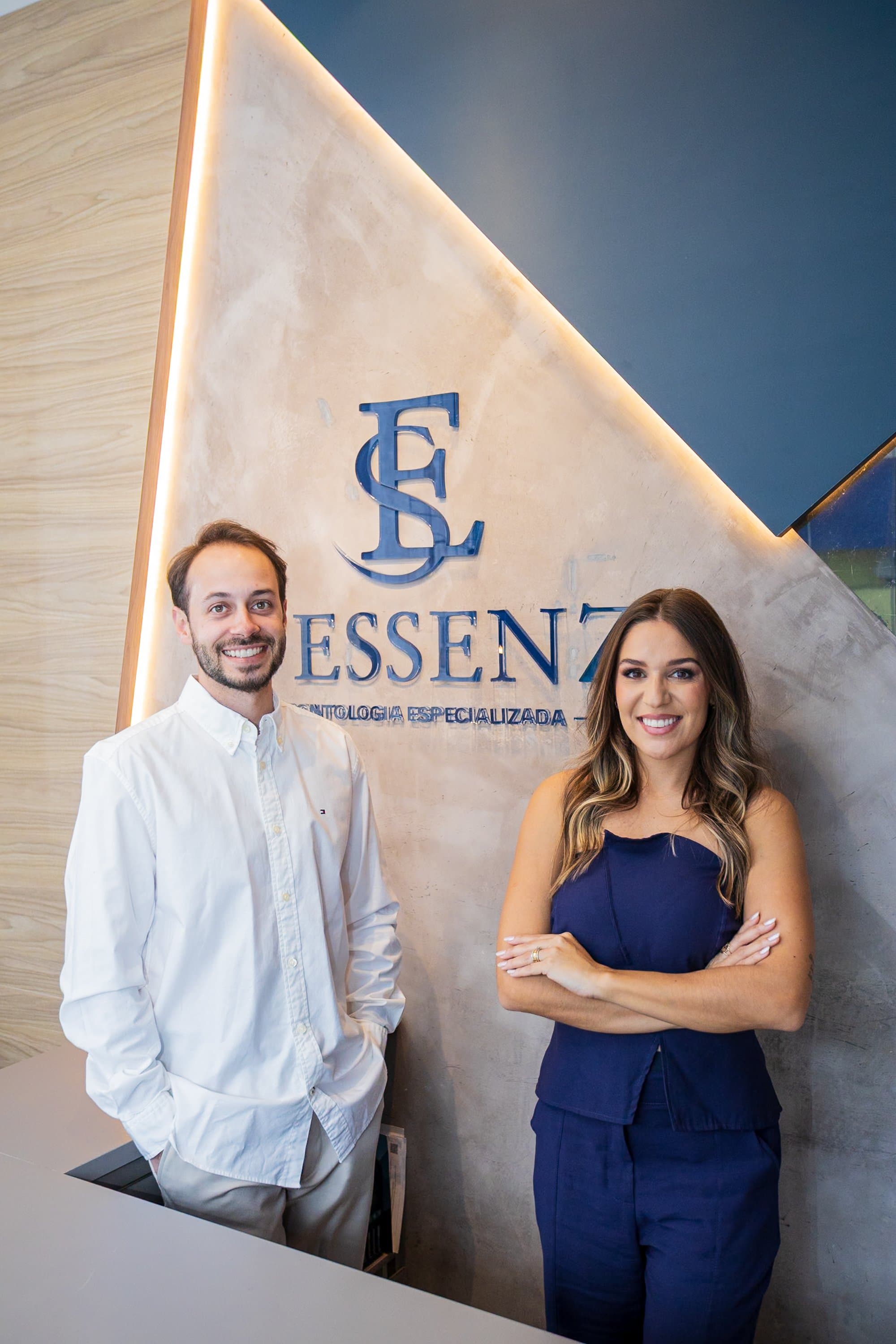 Dra. Deborah Marochi e Lucas na recepção da D'Essenz, junto à marca em destaque