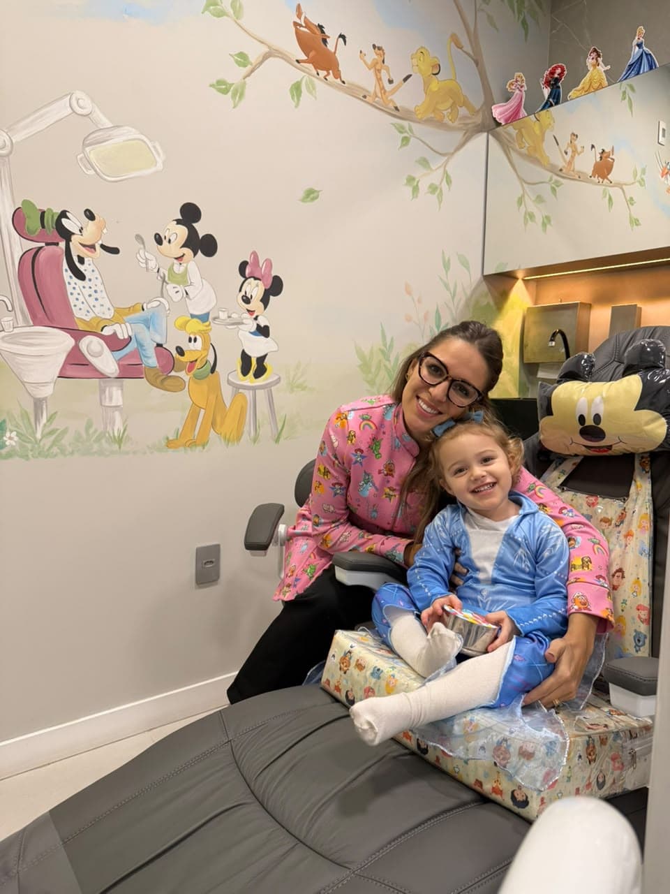Dentista da D'Essenz abraçando paciente sorridente fantasiada de princesa na cadeira da sala temática infantil
