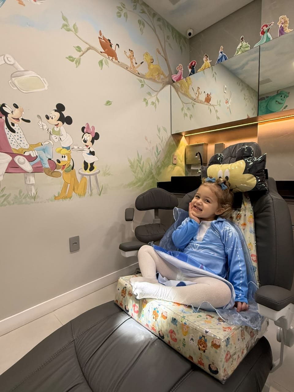 Criança sorrindo sentada na cadeira odontológica da sala temática infantil da D'Essenz
