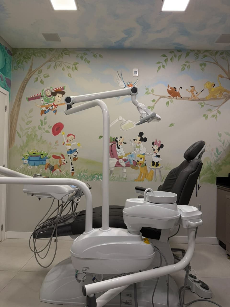 Cadeira odontológica em sala temática infantil da D'Essenz, com parede ilustrada com personagens da Disney