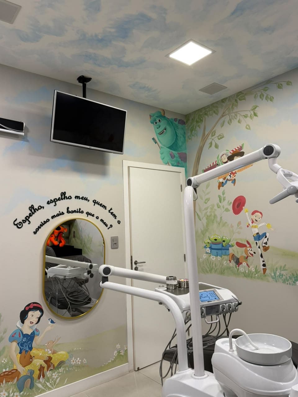 Sala de odontopediatria da D'Essenz com TV, espelho decorado e parede ilustrada com personagens da Disney